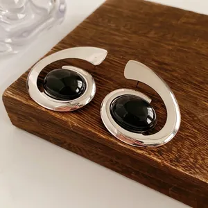 Vintage oval spiral double-layer earrings with black gemstones on walnut wood surface