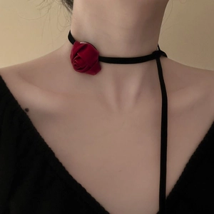 Close-up of a velvet choker with a deep red fabric rose on an elegant female model