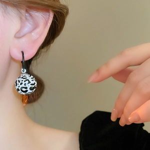 Élégantes boucles d'oreilles rondes à motif léopard noir et blanc portées par un mannequin