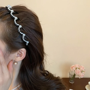 Detail of wavy pearl headband with assorted sizes on model with warm floral background
