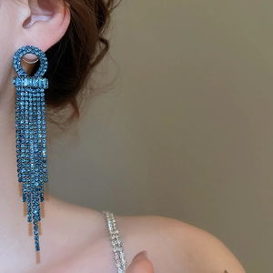 Close-up of blue zircon tassel earrings worn by a model in a side view portrait