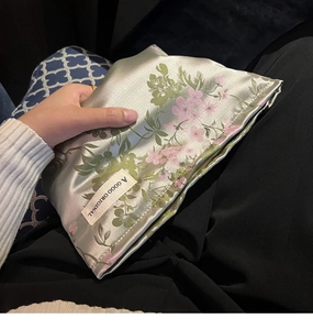 Detailed close-up of a satin floral pouch with elegant pink blossoms on light green fabric