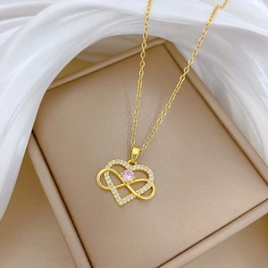 Gold double heart necklace with pink gemstone and crystals on white silk background