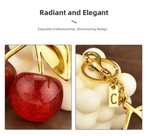 Detail of red glitter cherry keychain with golden leaf, lobster clasp and letter C tag