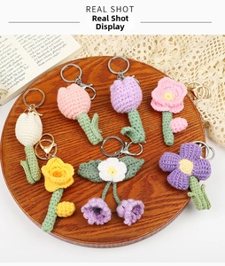 Detail of handmade crochet flower keychains featuring tulips and daisies on a wooden tray