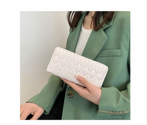 Detail of white quilted faux leather purse with zipper closure held by a model