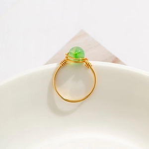 Macro detail of handmade gold wire ring with translucent emerald green stone bead