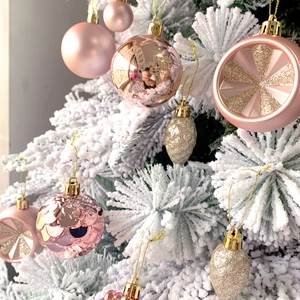 Pink and rose gold Christmas ornaments on a white tree with glossy and glitter finishes