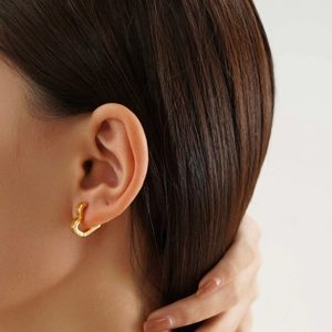 Gros plan d'une femme portant des boucles d'oreilles cœur en acier inoxydable doré chic