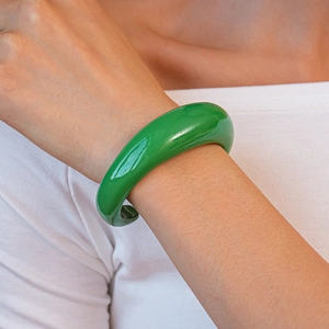 Primo piano di un bracciale rigido in acrilico verde brillante con finitura a specchio