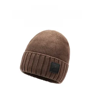 Detail view of dark brown ribbed knit beanie with mountain logo leather patch