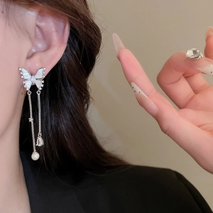 Detail view of butterfly tassel earring with shell texture and dangling silver chains