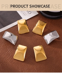 Detail of minimalist rectangular gold and silver earrings on textured leather background