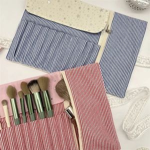 Detailed view of striped canvas makeup organizers with brush slots and mesh pockets