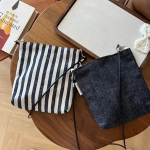 Flat lay of vintage striped and denim crossbody mini bags on a wooden table with books
