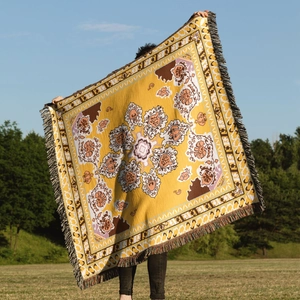 Detailed texture of bohemian yellow woven camping blanket with vintage floral patterns and tassels