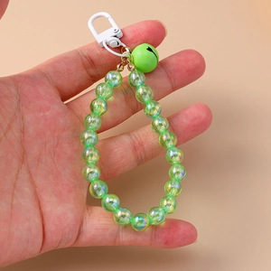 Detailed shot of green iridescent beads with matching bell and white clip on a phone charm