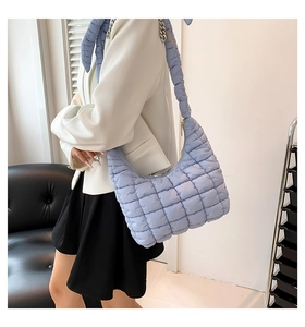 Close-up of light blue quilted hobo bag with thick padded strap and silver chain detail