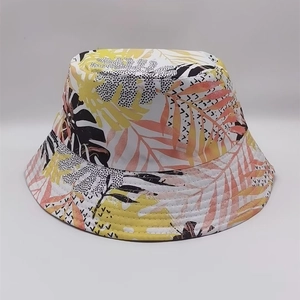 Reversible bucket hat featuring vibrant yellow and pink tropical leaf prints on white canvas