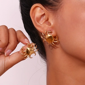 Primer plano de pendientes de cangrejo dorados en modelo con acabado chapado en oro 18k