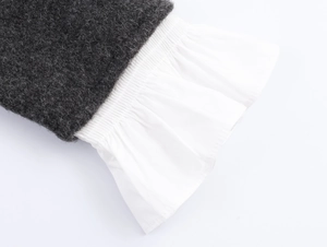 Detail of dark grey knit fabric stitched with white pleated cotton poplin hem