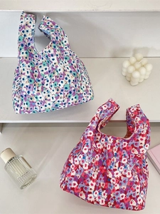Floral corduroy wrist bags in blue and pink patterns displayed on a white stand