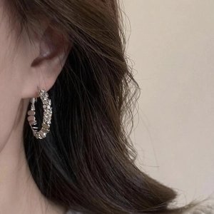 Close-up of elegant silver hoop earrings with shimmering pave-set crystals on ear lobe
