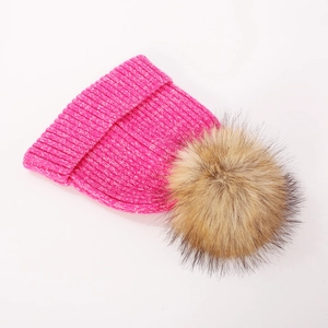 Close-up of bright pink ribbed knit beanie with a fluffy brown faux fur pom pom
