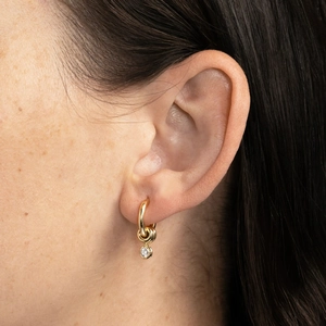 Close-up of model wearing gold hoop earrings with sparkling zircon charms for women