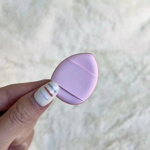 Close-up of hand holding a teardrop-shaped pink makeup sponge with soft sponge texture