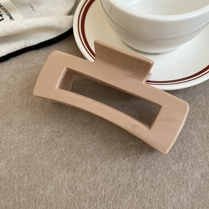 Detail view of the large square hollow hair claw clip in a matte nude finish on felt cloth
