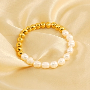 Close-up of baroque pearls and gold beads on elegant champagne silk background
