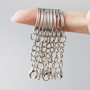 Detail of multiple silver metal keychains with chains and lobster clasps on fingers