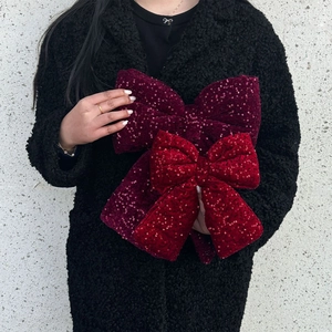 Large sequin Christmas bows in red and burgundy held by a model for holiday decor