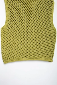 Detailed macro view of grass green hollow knit texture on this sleeveless sweater vest