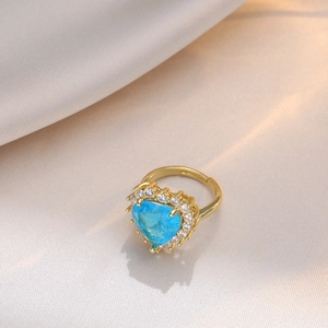 Adjustable gold ring with heart-shaped blue zircon stone on white satin fabric