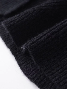 Close-up of the black ribbed knit fabric showing detailed texture of the cardigan