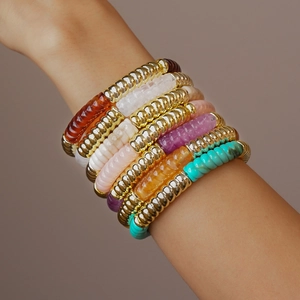 Détail de bracelets empilés en perles acryliques colorées et perles dorées filetées
