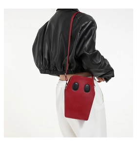 Detail of red coffin shaped crossbody bag in PU leather shown on a model in a back view