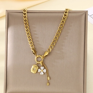 Detailed close-up of gold chain necklace with flower pendant and star-engraved charm