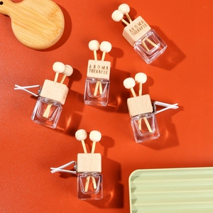 Flat lay of five square glass car perfume bottles with wooden caps and vent clips