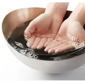 Close-up of black knitted beanie being hand-washed in soapy water to show durability