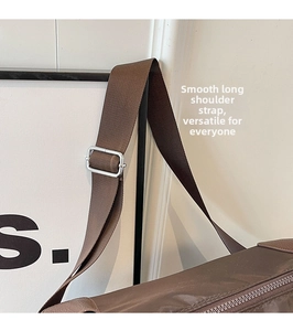 Detail of adjustable wide nylon shoulder strap with silver buckle on brown crossbody bag