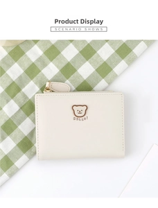 Close-up of cream PU leather wallet with cute bear emblem and gold zipper detail
