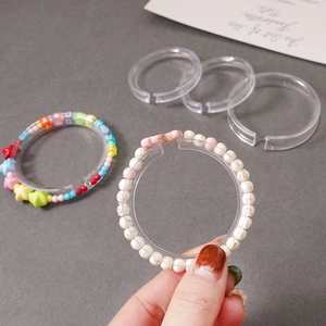 Macro detail of transparent acrylic C-ring display holder for beaded bracelets and jewelry
