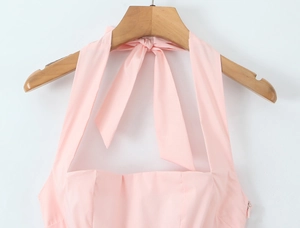 Detail view of pink halter neck dress with stylish bow tie on a wooden hanger
