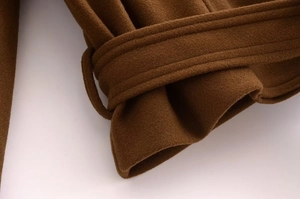 Detail of brown wool coat sleeve featuring decorative strap and high-quality buckle