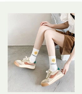 Close-up of white cotton socks with a yellow smile icon paired with retro sneakers