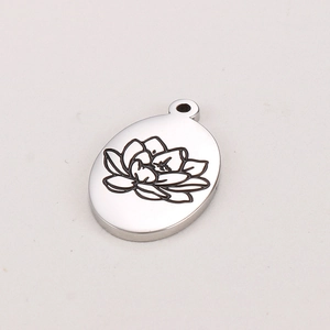 Gros plan du pendentif ovale en acier inoxydable argenté avec gravure de fleur de lotus