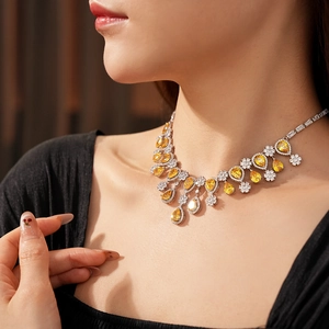 Detailed close-up of a drop-shaped yellow gemstone necklace with white zircon accents